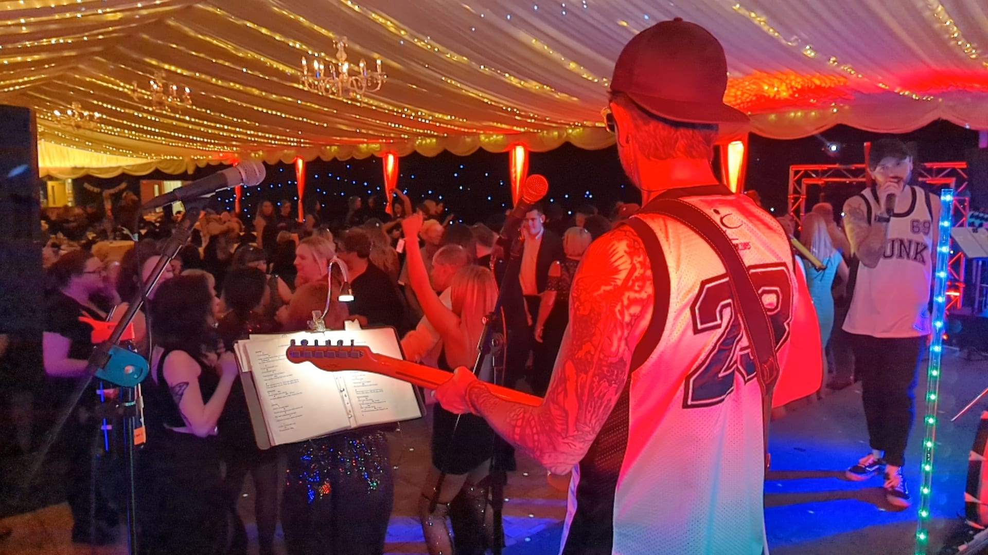 The view from behind the guitarist: a full marquee floor under festoon lights