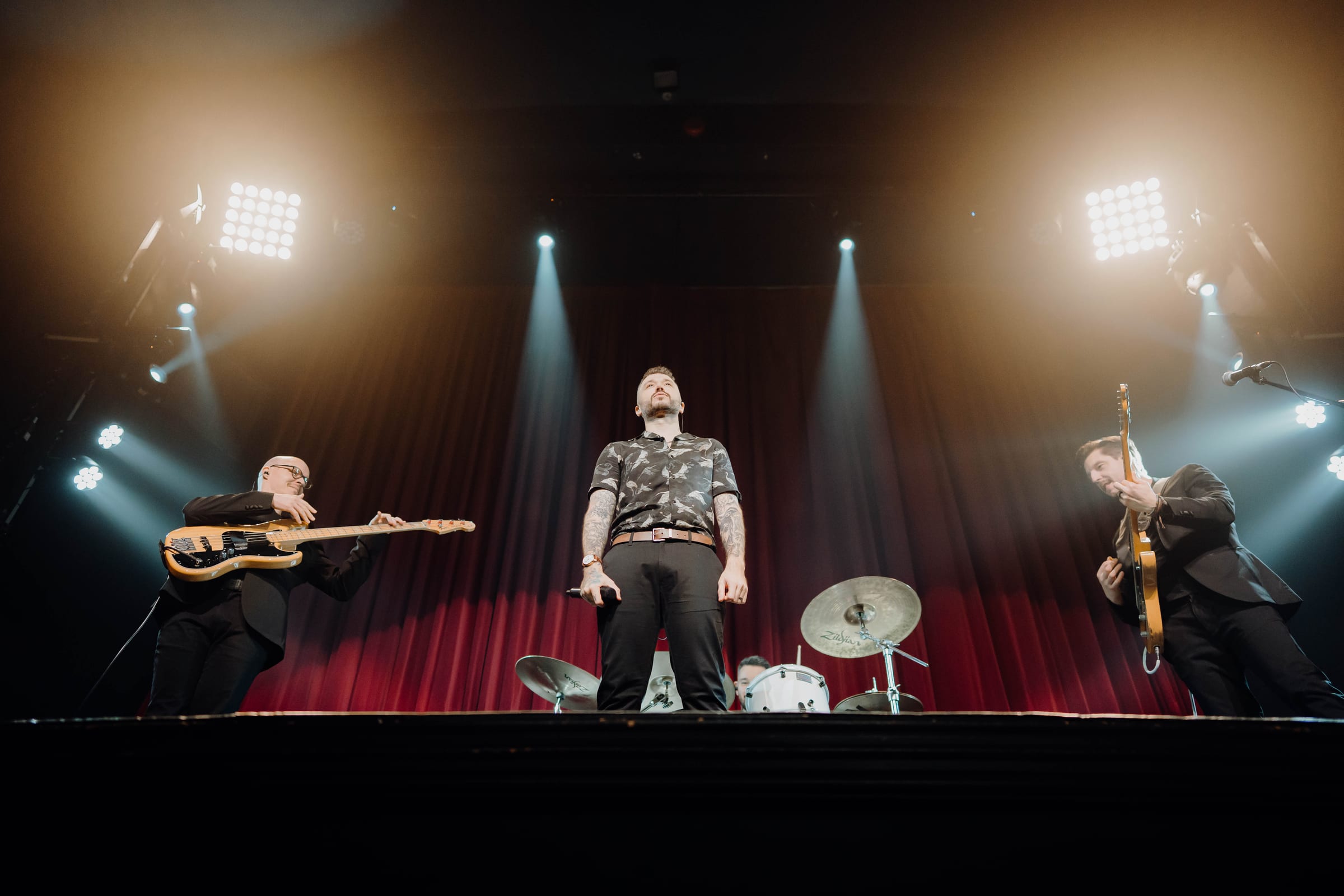 All four of the band lit by crossed overhead beams