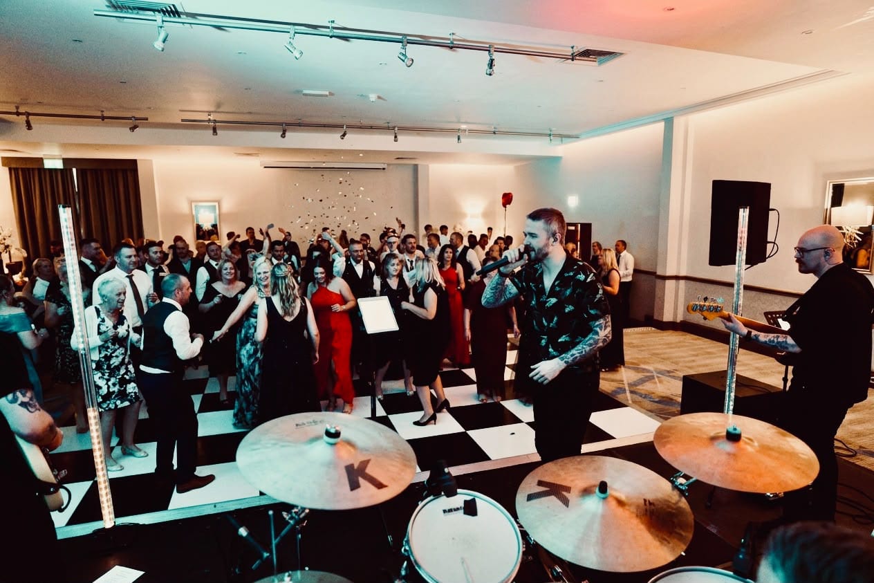 The singer facing a full dancefloor of formally dressed guests in a hotel function room